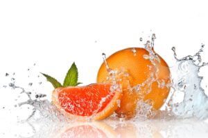 Water splash on grapefruit with mint isolated on white